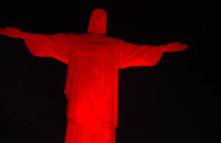 Cristo Redentor recebe iluminação vermelha para marcar Dia Nacional de Luta da População em Situação de Rua